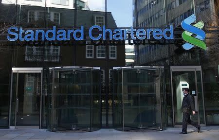 A man walks past the head office of Standard Chartered bank in the City of London February 27, 2015. REUTERS/Eddie Keogh