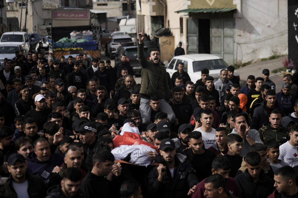 Mourners carry the body of Mahmoud Abu Haniyeh, 17, during his funeral at the town of Azzun, West Bank, Sunday, Dec. 10, 2023. The Palestinian Health Ministry says Abu Haniyeh was killed during clashes with the Israeli army on Saturday in the town of Azzun. (AP Photo/Majdi Mohammed)