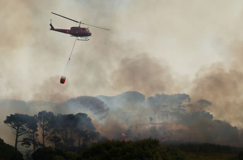 A helicopter battles to contain a bushfire that broke out on the slopes of Table Mountain above the memorial to Cecil John Rhodes in Cape Town