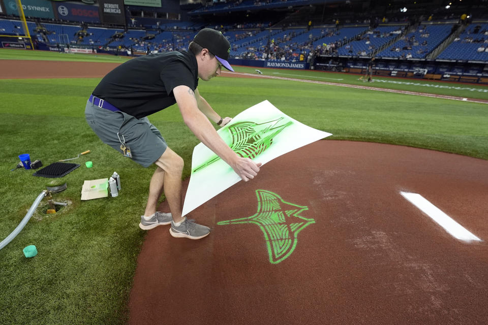 Tampa Bay Rays grounds crew member Cameron Merrick finishes painting the new City Connect logo on the back of the pitcher's mound before a baseball game against the New York Mets Friday, May 3, 2024, in St. Petersburg, Fla. (AP Photo/Chris O'Meara)