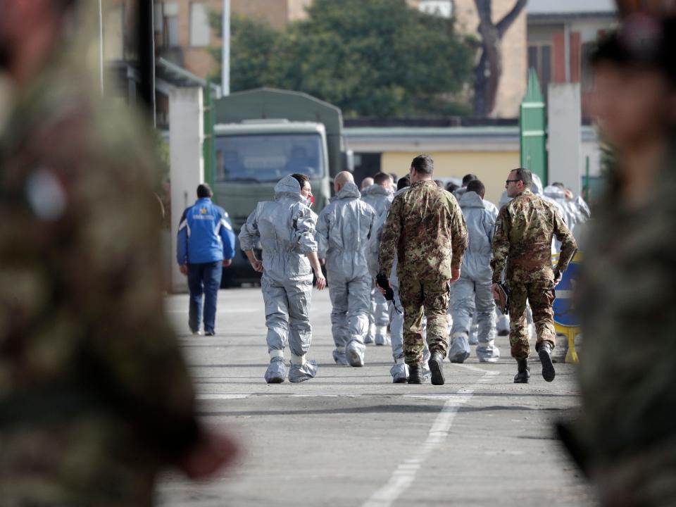 People wearing protective suits and military personnel walk inside a military complex where 56 Italians evacuated from Wuhan, China, will be kept in quarantine upon their arrival Monday, Feb. 3, 2020, on the outskirts of Rome. A viral outbreak that began in China has infected more than 17,300 people and 361 deaths as of Monday, Italy has two cases reported. (AP Photo/Andrew Medichini)