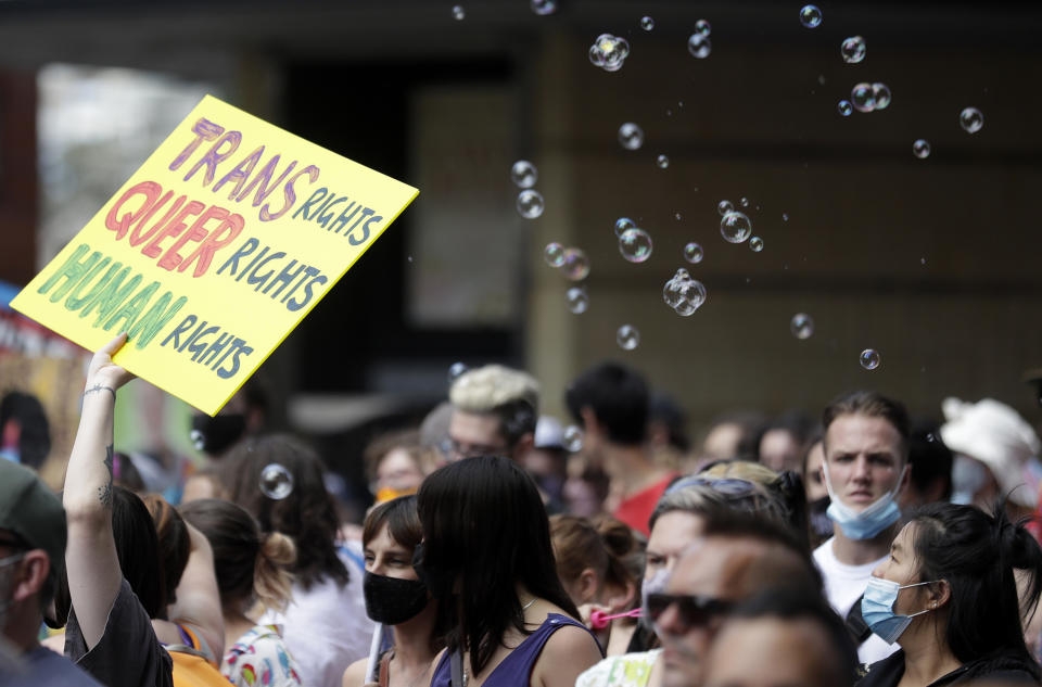 Bubbles float in the air as a placard is held up while hundreds of protesters march in Sydney, Saturday, March 6, 2021, ahead of the annual Gay and Lesbian Mardi Gras. The protesters say they want to restore the protest roots of Mardi Gras and challenge systems of injustice. (AP Photo/Rick Rycroft)