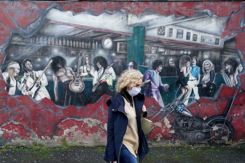 FILE PHOTO: A woman walks past a wall mural during the resurging coronavirus ouitbreak in Galway, Ireland