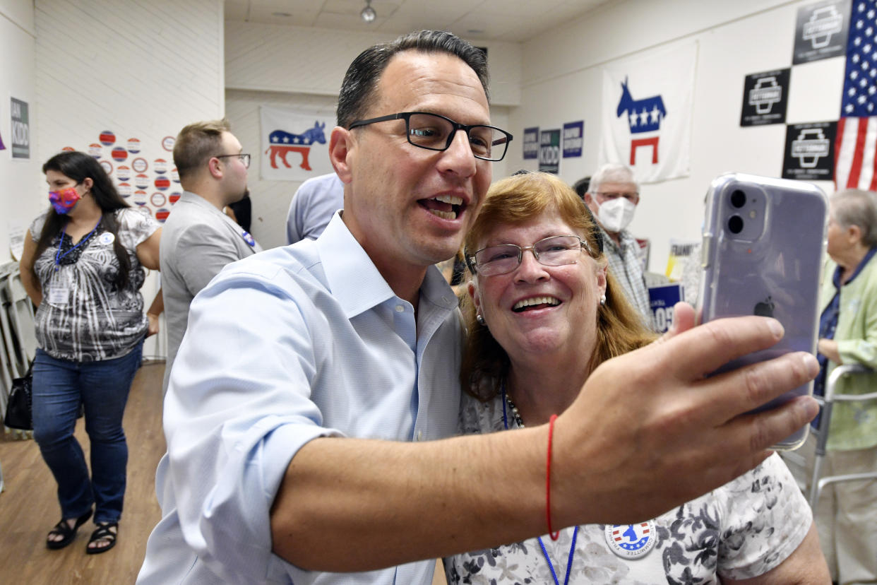 Josh Shapiro holds up a cellphone in front of himself and a woman to record a video message.