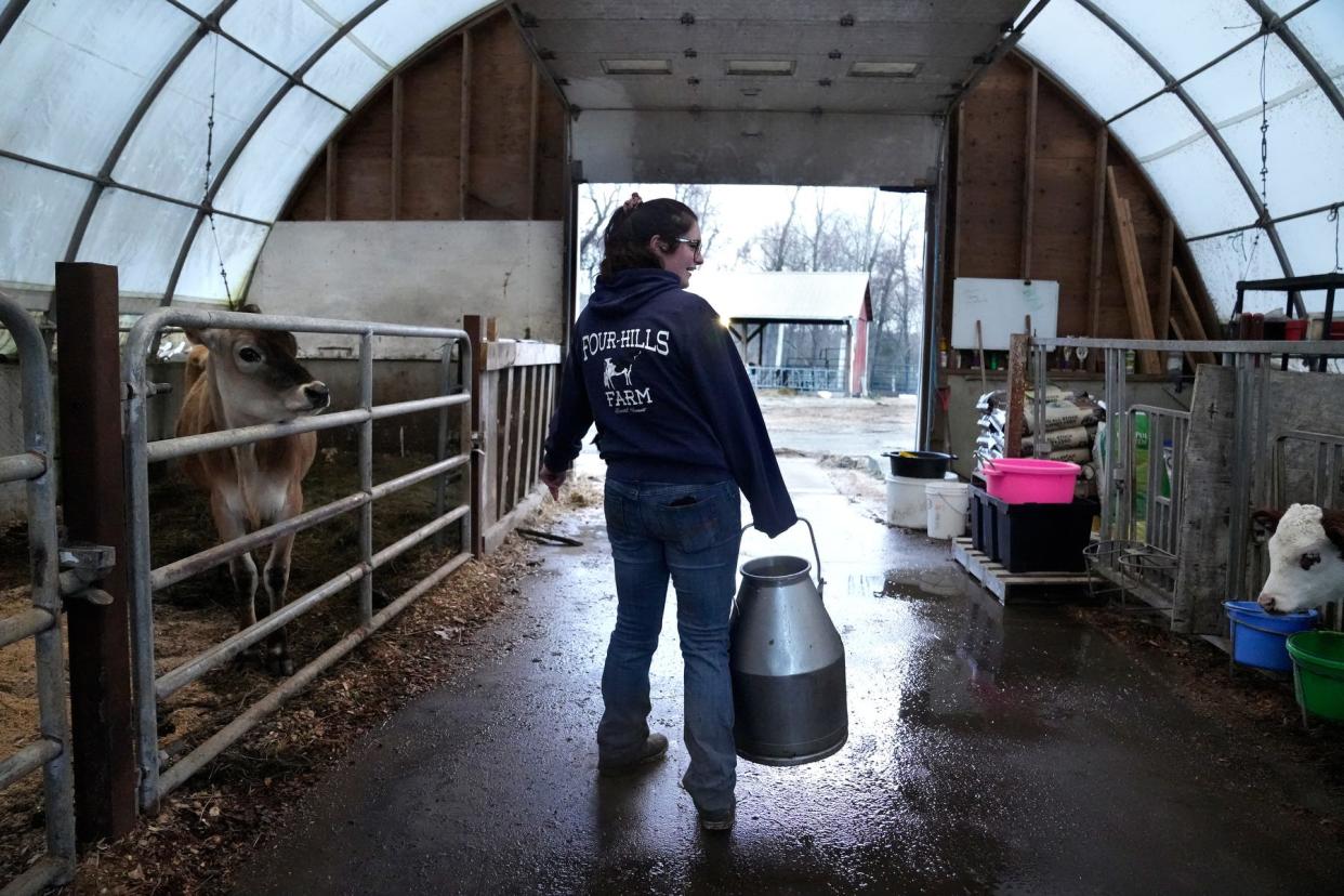 Maggie Cole stands in the calf barn with an empty milk can after feeding her collection of calves on an early April Saturday morning as she works the family farm, EMMA Acres, in Exeter. The farm name came from the first initials of Maggie and her three older siblings, Elizabeth, Matthew and Alex.