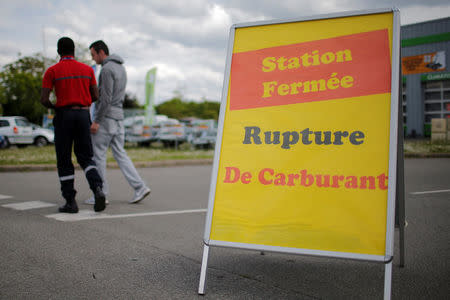 A security officer and a customer walk behind a placard which reads "Out of fuel" at a petrol station in Reze near Nantes, France, May 24, 2016. REUTERS/Stephane Mahe