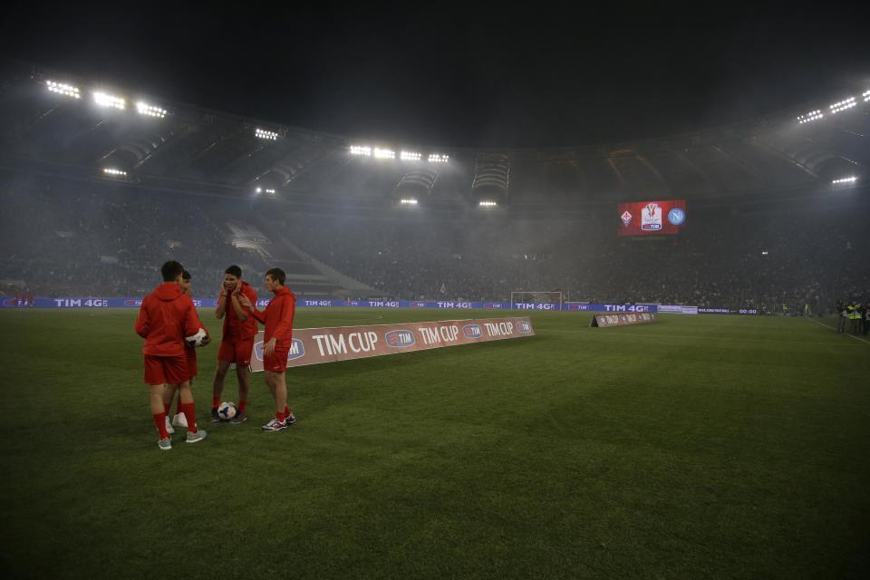 Pitch attendant cover their ears as fireworks are blasted prior to the start of Italian Cup final match between Fiorentina and Napoli in Rome's Olympic stadium Saturday, May 3, 2014. At least one fan and one police officer were reportedly shot before the Italian Cup final between Napoli and Fiorentina, and the fan was in serious condition. As a result, the start of the final was delayed, and there were scenes of violence inside the stadium with a firefighter injured by fireworks thrown from the stands. The shootings occurred in an area where Napoli fans were gathering for the match, the ANSA news agency reported. (AP Photo/Gregorio Borgia)