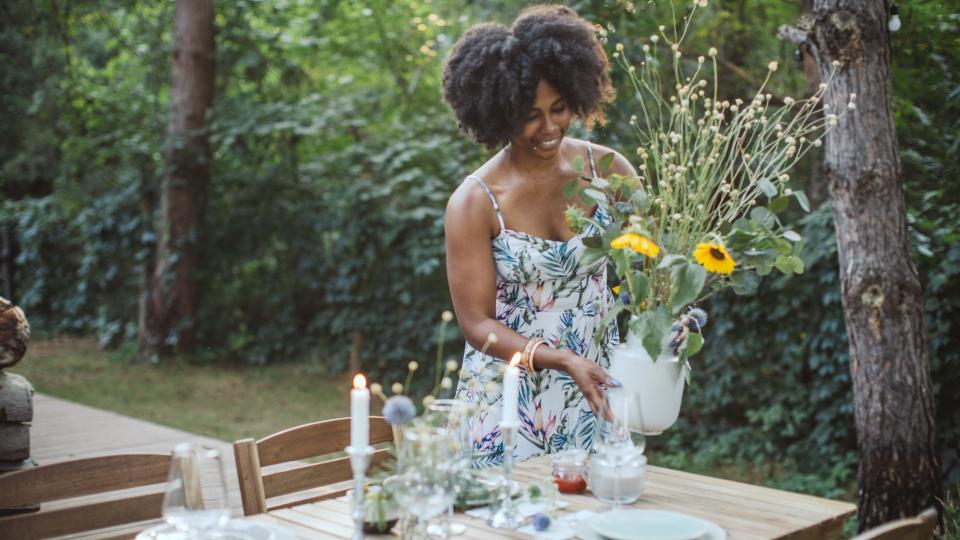 Woman preparing dinner table in backyard of the cottage.