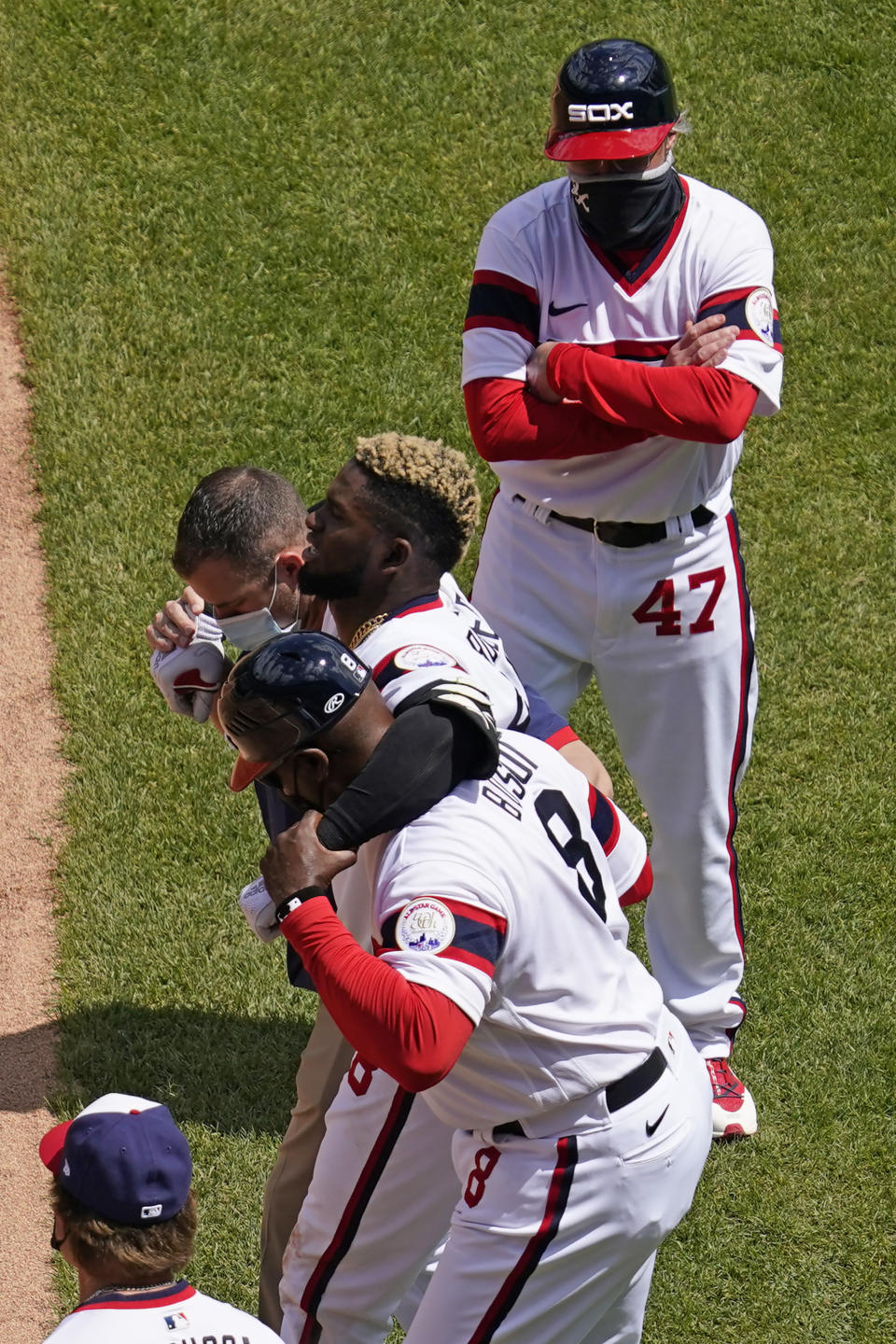 Chicago White Sox's Luis Robert (88) leaves with a team trainer and first base coach Daryl Boston as Chicago White Sox third-base coach Joe McEwing (47) watches during the first inning of a baseball game against the Cleveland Indians in Chicago, Sunday, May 2, 2021. (AP Photo/Nam Y. Huh)