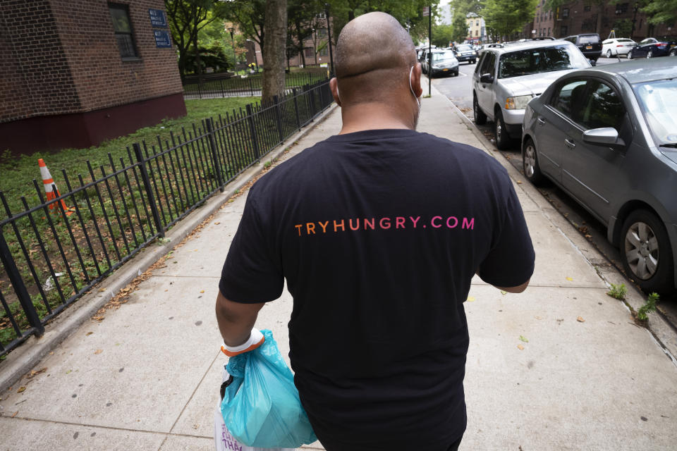 Driver Frank Robinson delivers prepackaged meals Tuesday, July 7, 2020 in New York. Robinson is one of 200 drivers paid by catering startup HUNGRY to deliver prepackaged meals to stay-at-home elderly and low-income kids. (AP Photo/Mark Lennihan)
