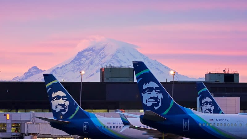 Alaska Airlines planes are parked at gates with Mount Rainier in the background at sunrise, on March 1, 2021, at Seattle-Tacoma International Airport in Seattle.