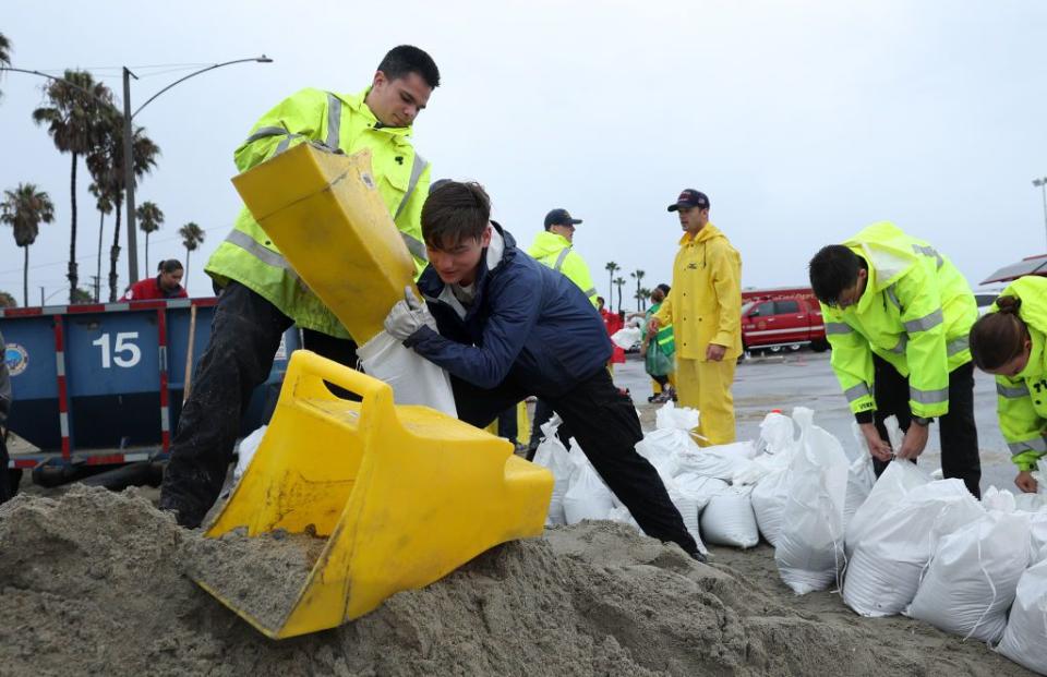 Volunteers and members of the Long Beach Fire Department fill sandbags at Belmont Shore Beach on Sunday as Tropical Storm approaches.