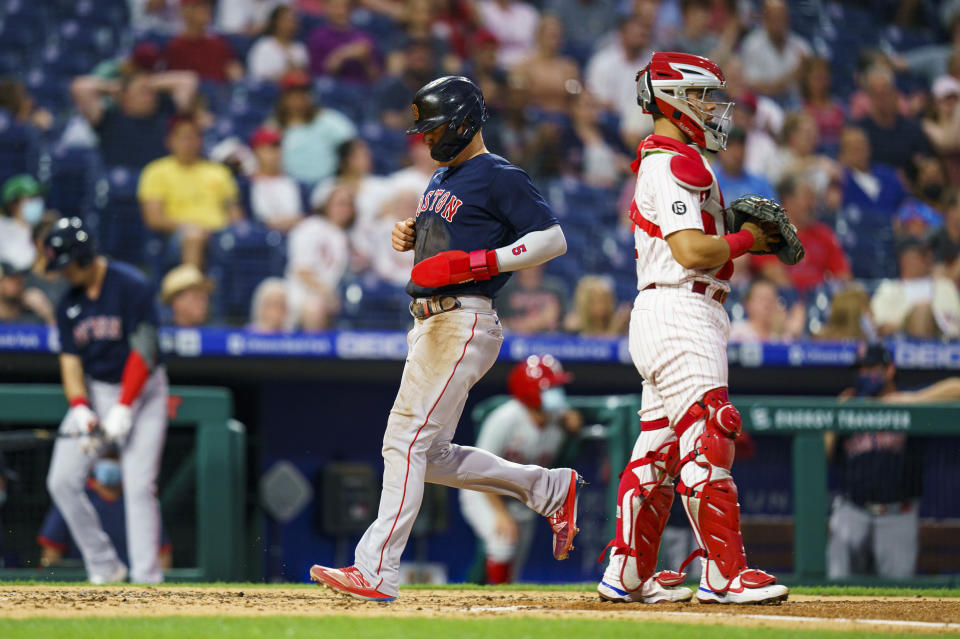 Boston Red Sox's Enrique Hernandez, left, scores on a sacrifice fly by Xander Bogaerts as Philadelphia Phillies catcher Rafael Marchan stands near the plate during the third inning of a baseball game Saturday, May 22, 2021, in Philadelphia. (AP Photo/Chris Szagola)