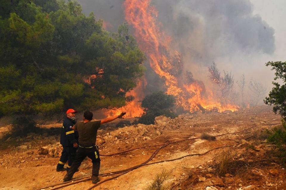 Locals help firefighters as they try to extinguish a wildfire burning near the village Vlyhada near Athens (Getty Images)