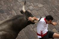 <p>Un joven intenta evitar con su brazo la cornada de un toro durante el encierro (EFE) </p>