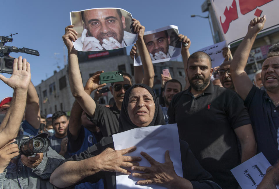 Maryam Banat, 67, mother of Palestinian Authority outspoken critic Nizar Banat holds a poster with his picture while attending a rally protesting his death, in the West Bank city of Ramallah, Saturday, July 3, 2021. Hundreds of Palestinians gathered to demonstrate against President Mahmoud Abbas, hoping to inject new momentum into a protest movement sparked by the death of an outspoken critic in the custody of security forces. (AP Photo/Nasser Nasser)