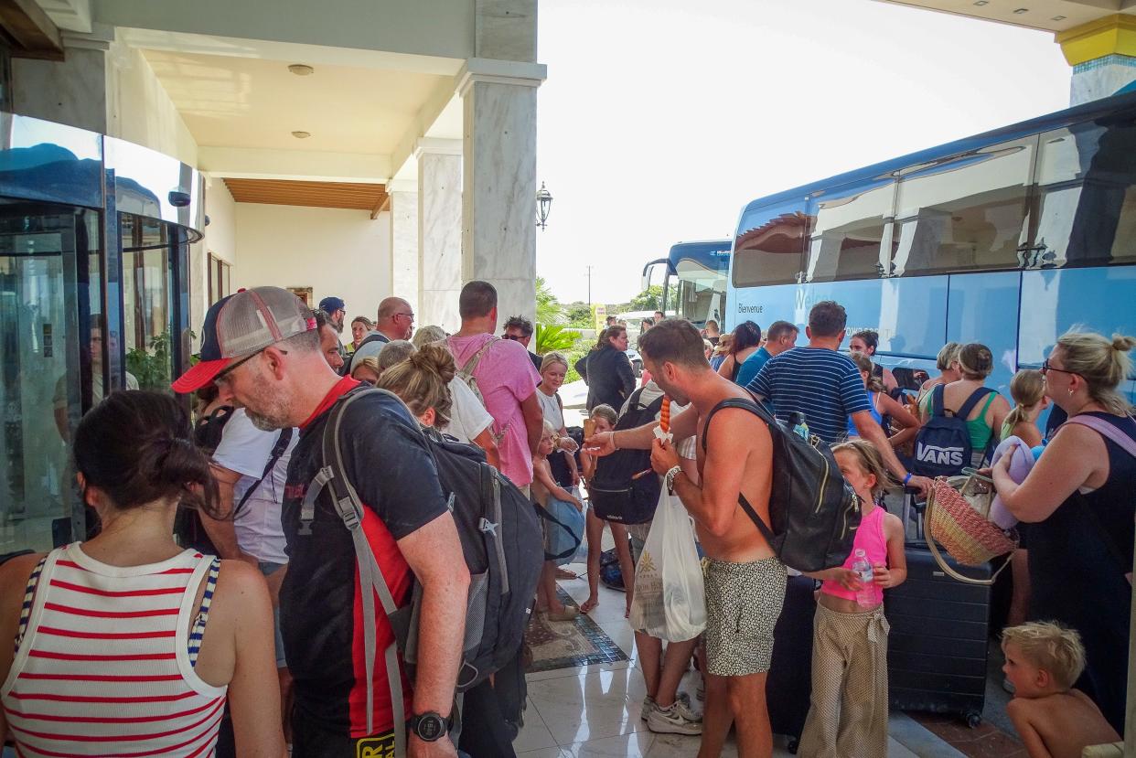Evacuees wait to board buses as they leave their hotel during a forest fire on the island of Rhodes, Greece, on July 23, 2023.