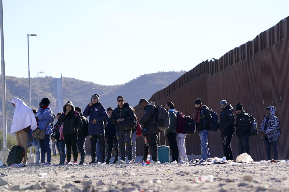 Migrants wait for shuttle buses for transport as they join hundreds of migrants gathering along the border Tuesday, Dec. 5, 2023, in Lukeville, Ariz. The U.S. Border Patrol says it is overwhelmed by a shift in human smuggling routes, with hundreds of migrants from faraway countries like Senegal, Bangladesh and China being dropped in the remote desert area in Arizona. (AP Photo/Ross D. Franklin)