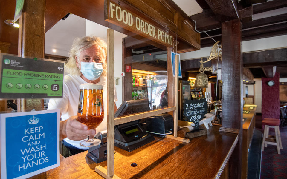 Phil Weaver, owner of The Old Smithy pub in Church Lawford, Warwickshire holds a pint of beer from behind a protective screen, as pub and hospitality bosses have cheered the Government's proposals to allow customers through their doors again on July 4 as "a welcome relief".