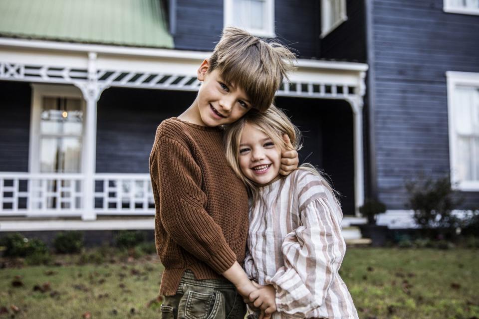 portrait of brother and sister in front of farmhouse