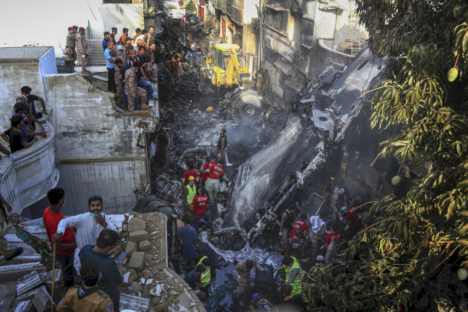 Volunteers look for survivors of a plane that crashed in a residential area of Karachi, Pakistan, May 22, 2020. An aviation official says a passenger plane belonging to state-run Pakistan International Airlines crashed near Karachi's airport. (AP Photo/Fareed Khan)