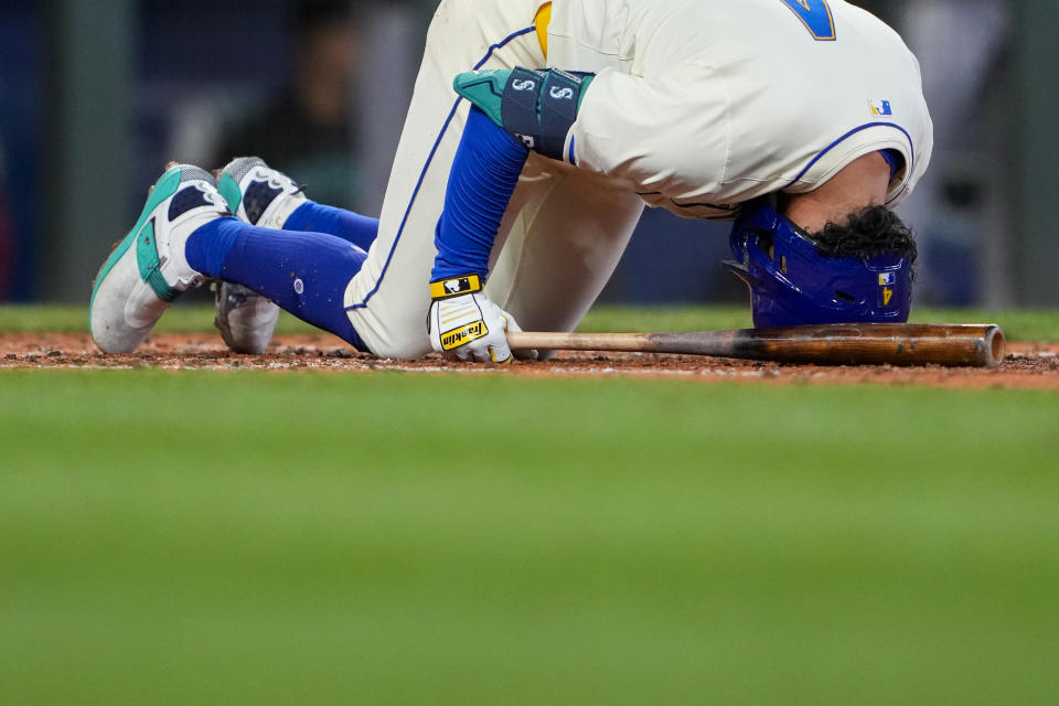 Seattle Mariners' Josh Rojas rests his head on the ground after fouling a ball off his foot against the Arizona Diamondbacks during the fifth inning of a baseball game Sunday, April 28, 2024, in Seattle. (AP Photo/Lindsey Wasson)