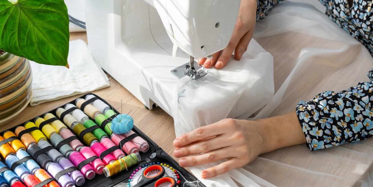 woman hand close up sews tulle on electric sewing machine