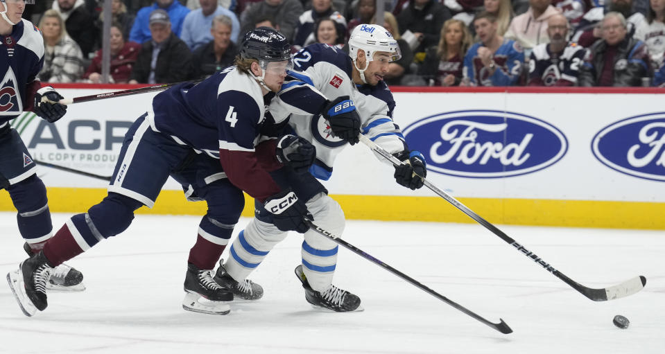 Winnipeg Jets right wing Nino Niederreiter, right, shoots the puck next to Colorado Avalanche defenseman Bowen Byram during the second period of an NHL hockey game Thursday, Dec. 7, 2023, in Denver. (AP Photo/David Zalubowski)