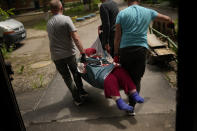 A woman is carried from her home in an evacuation by volunteers of Vostok SOS charitable organisation in Kramatorsk, eastern Ukraine, Thursday, May 26, 2022. Residents in villages and towns near the front line continue to flee as fighting rages in eastern Ukraine. (AP Photo/Francisco Seco)