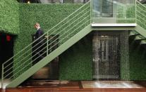 A man walks down stairs next to a waterfall at THE OUT NYC. This is one of three courtyards that has a pair of hot tubs, a water wall, and cabanas.