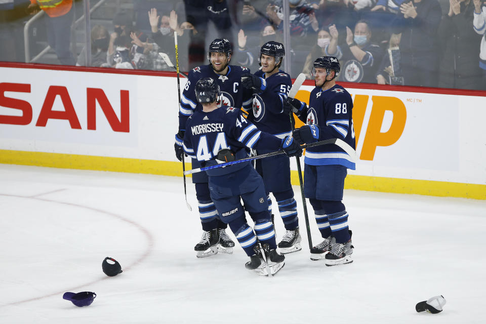 Winnipeg Jets' Josh Morrissey (44), Blake Wheeler (26), Mark Scheifele (55) and Nate Schmidt (88) celebrate Scheifele's hat-trick goal against the New Jersey Devils, during the third period of an NHL hockey game Friday, Dec. 3, 2021, in Winnipeg, Manitoba. (John Woods/The Canadian Press via AP)