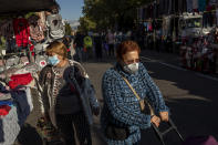 Customers wearing masks to prevent the spread of the coronavirus walk through street stalls at a market in Madrid, Spain, on Tuesday, October 13, 2020 (AP Photo/Bernat Armangue)