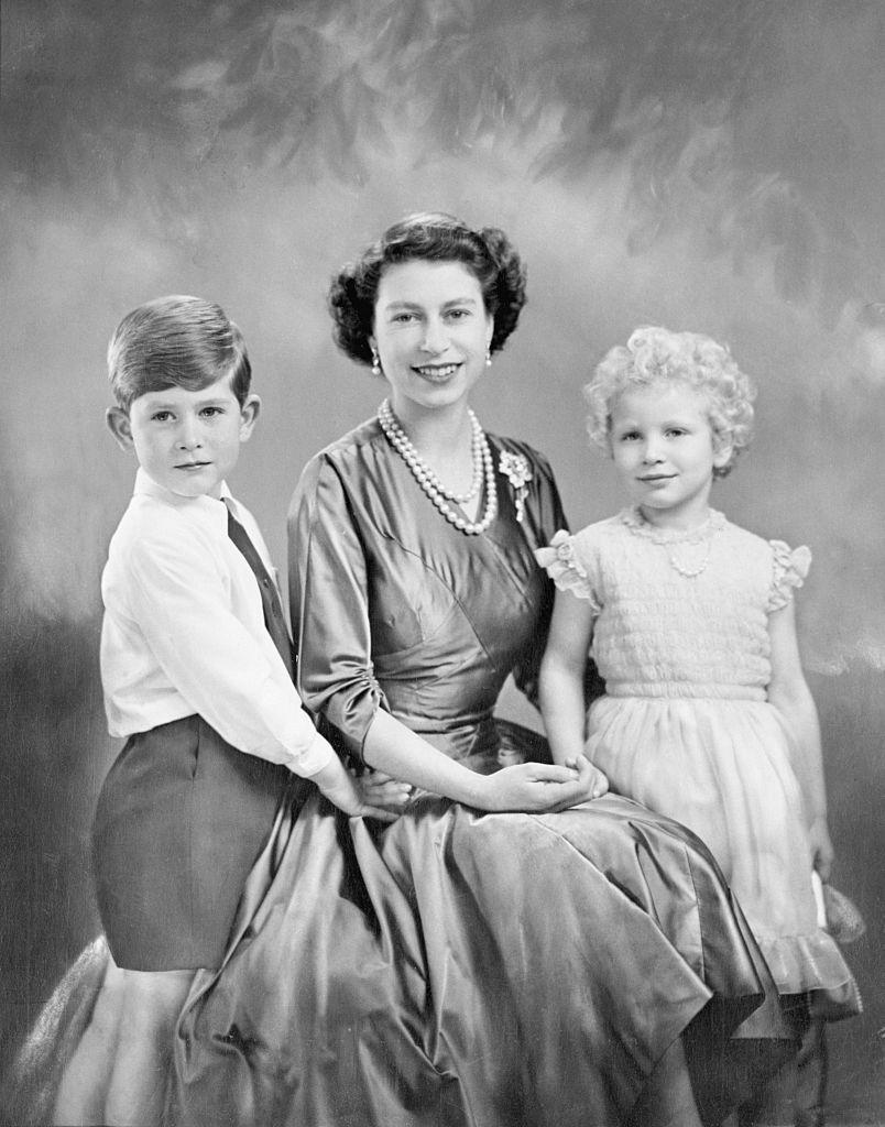 <p>Queen Elizabeth II, Charles and Anne smile as they have a portrait taken. The two children can be seen sweetly holding their mother.</p>