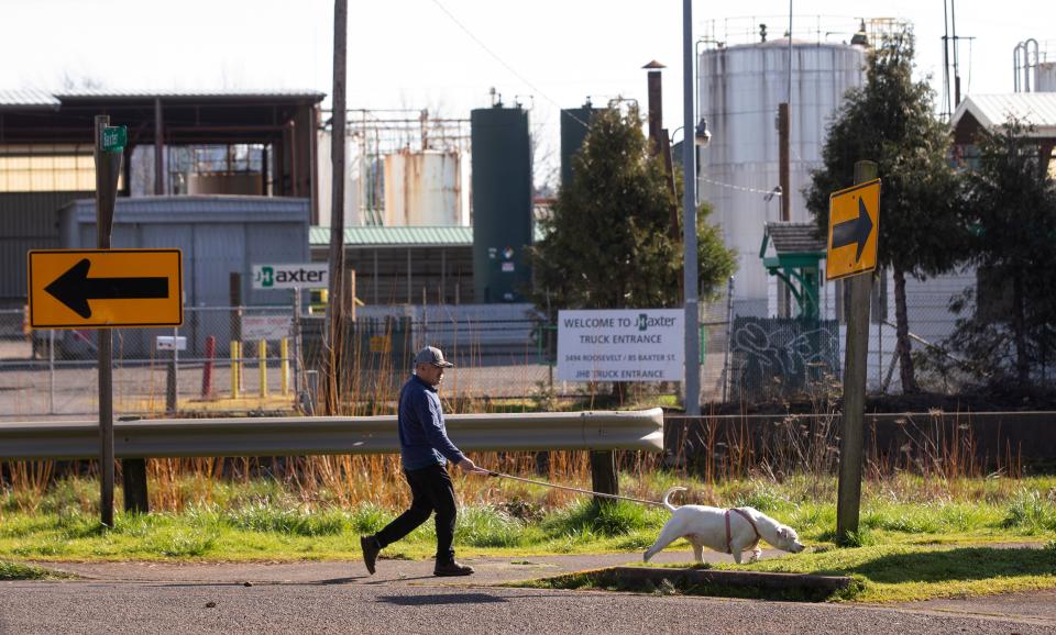 A man and his dog walk in a neighborhood near the shuttered J.H. Baxter & Co. plant in Eugene. 