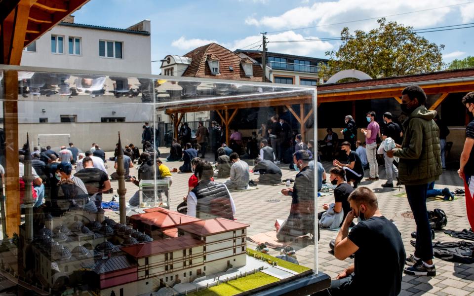 Worshippers praying in the temporary mosque's courtyard due to a lack of space inside, where a model of the new mosque is on display -  Bruno Fert