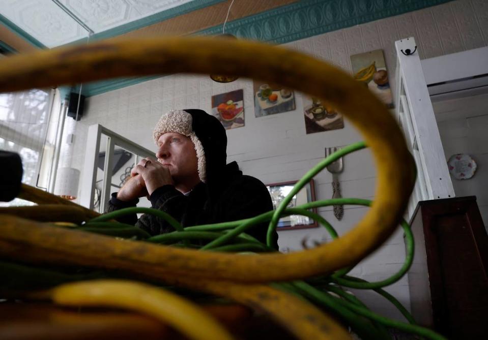 Tom Markey, an employee at Betsy’s Crepes, sits next to power cords meant to supply a generator inside the restaurant on Monday, Dec. 5, 2022, in Southern Pines, N.C. 