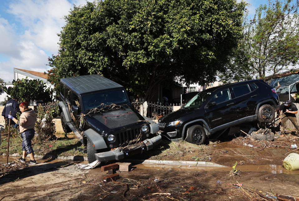 A person works to help tow away a vehicle dislodged by flooding the day after an explosive rainstorm caused flooding in areas of San Diego County on Jan. 23, 2024 in San Diego.