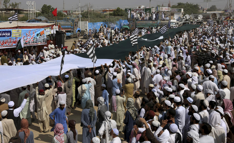 Supporters of the Jamiat Ulema-e-Islam party display a huge Pakistani flag while they gather to start an anti-government march, in Karachi, Pakistan, Sunday, Oct. 27, 2019. Thousands of supporters of the ultra-religious party are gathering in Karachi to start a large anti-government march on Pakistan's capital farther north. (AP Photo/Fareed Khan)