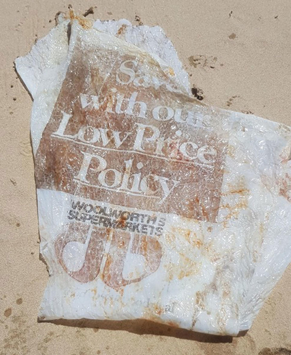 A tattered Woolworths plastic bag, estimated to be up to 30 years old, washed up on a Queensland beach.