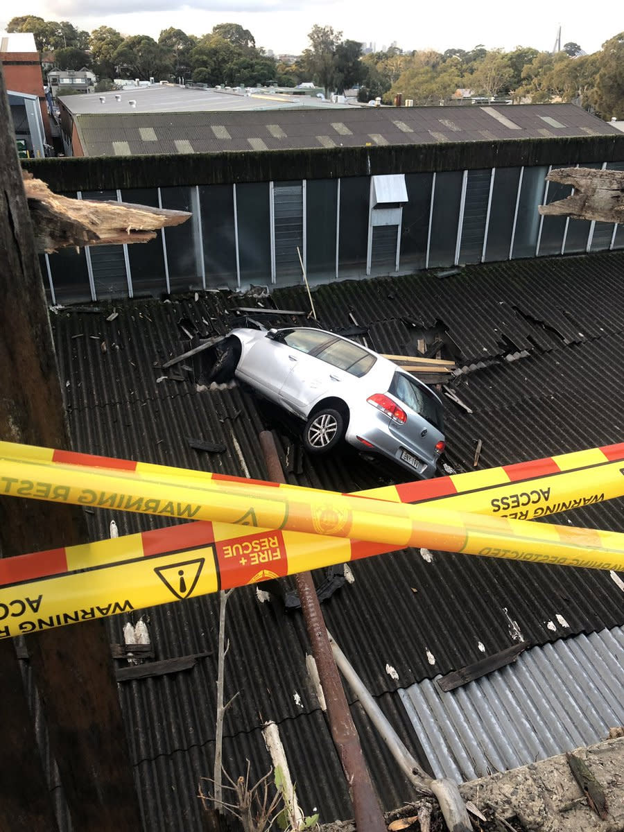 The car can be seen embedded in the roof behind police tape. 