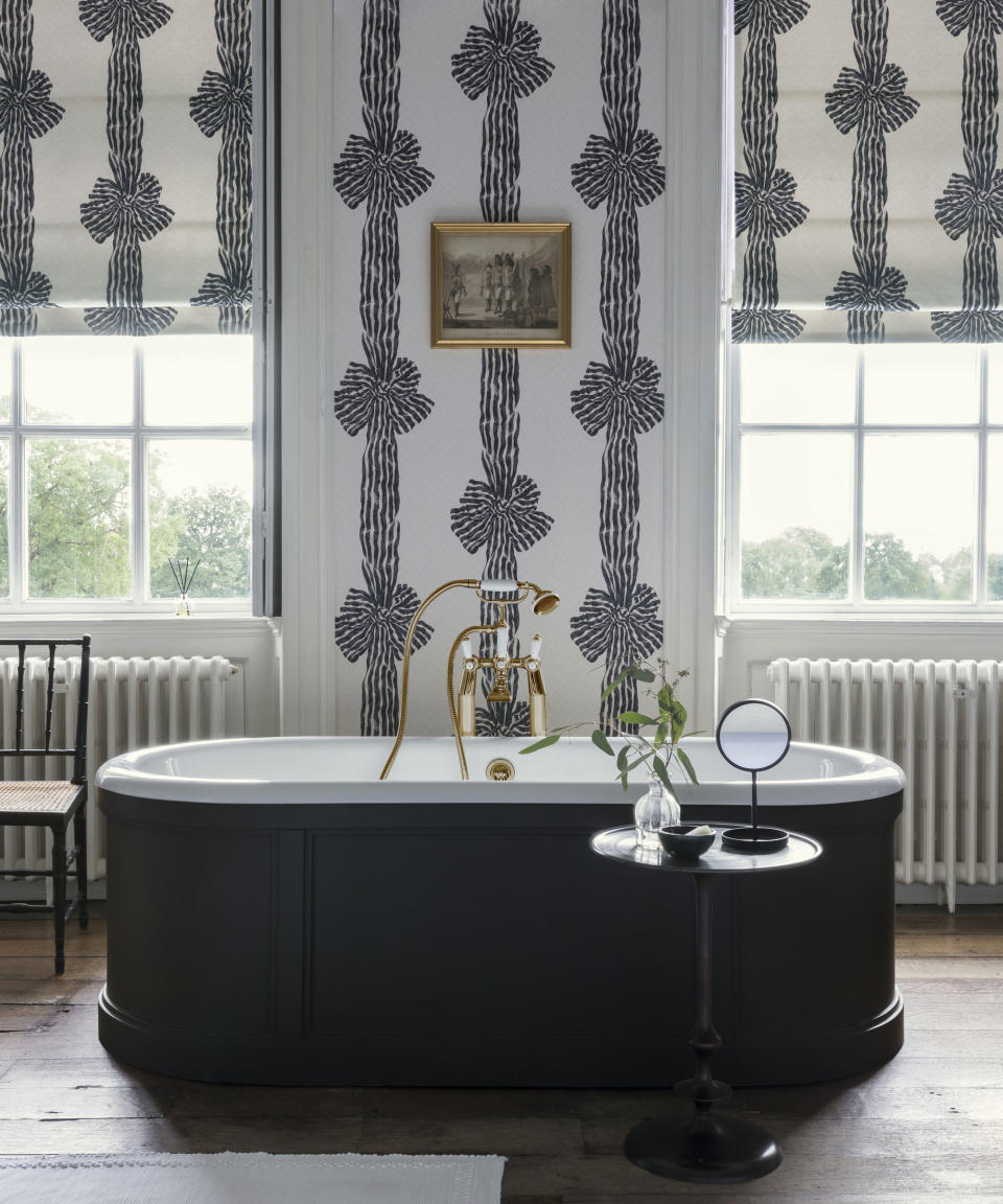 A large black bathtub in a bathroom with monochrome patterned wallpaper