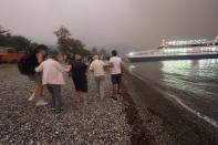 People embark a ferry during an evacuation from Kochyli beach as wildfire approaches near Limni village on the island of Evia, about 160 kilometers (100 miles) north of Athens, Greece, Friday, Aug. 6, 2021. Thousands of people fled wildfires burning out of control in Greece and Turkey on Friday, including a major blaze just north of the Greek capital of Athens that claimed one life, as a protracted heat wave left forests tinder-dry and flames threatened populated areas and electricity installations. (AP Photo/Thodoris Nikolaou)