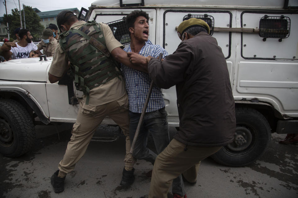 Indian policemen detain a Kashmiri Shiite Muslim as he attempts with others to take out a religious procession in Srinagar, Indian controlled Kashmir, Friday, Aug. 28, 2020. Police and paramilitary soldiers on Friday detained dozens of Muslims participating in religious processions in the Indian portion of Kashmir. Authorities had imposed restrictions in parts of Srinagar, the region's main city, to prevent gatherings marking Muharram from developing into anti-India protests. (AP Photo/Mukhtar Khan)