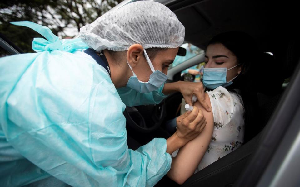 A health worker administers a dose to a woman during a day of vaccination at a drive-in in Brasilia - Alves/EPA-EFE/Shutterstock