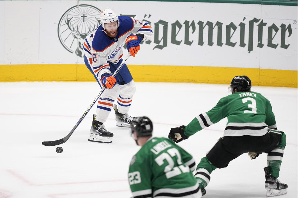 Edmonton Oilers right wing Connor Brown (28) looks to clear the puck against Dallas Stars' Chris Tanev (3) and Esa Lindell (23) during the third period in Game 2 of the Western Conference finals in the NHL hockey Stanley Cup playoffs Saturday, May 25, 2024, in Dallas. (AP Photo/Tony Gutierrez)