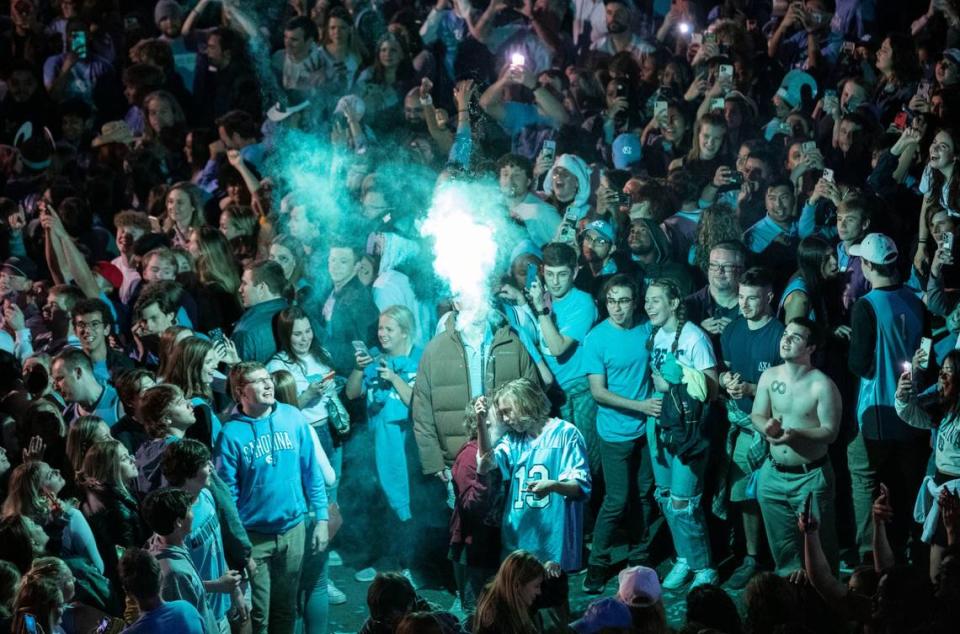 A Tar Heel fan launches a firework that lights up a celebrating crowd at the intersection of Franklin and Columbia Streets in Chapel Hill, N.C., after a historic win against Duke in the Final Four on April 2, 2022.