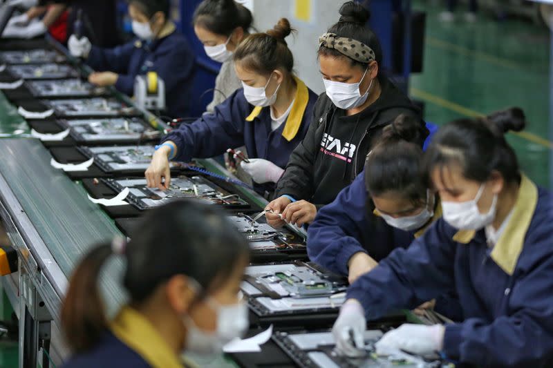 FILE PHOTO: Employees wearing masks work on a production line manufacturing display monitors at a TPV factory in Wuhan