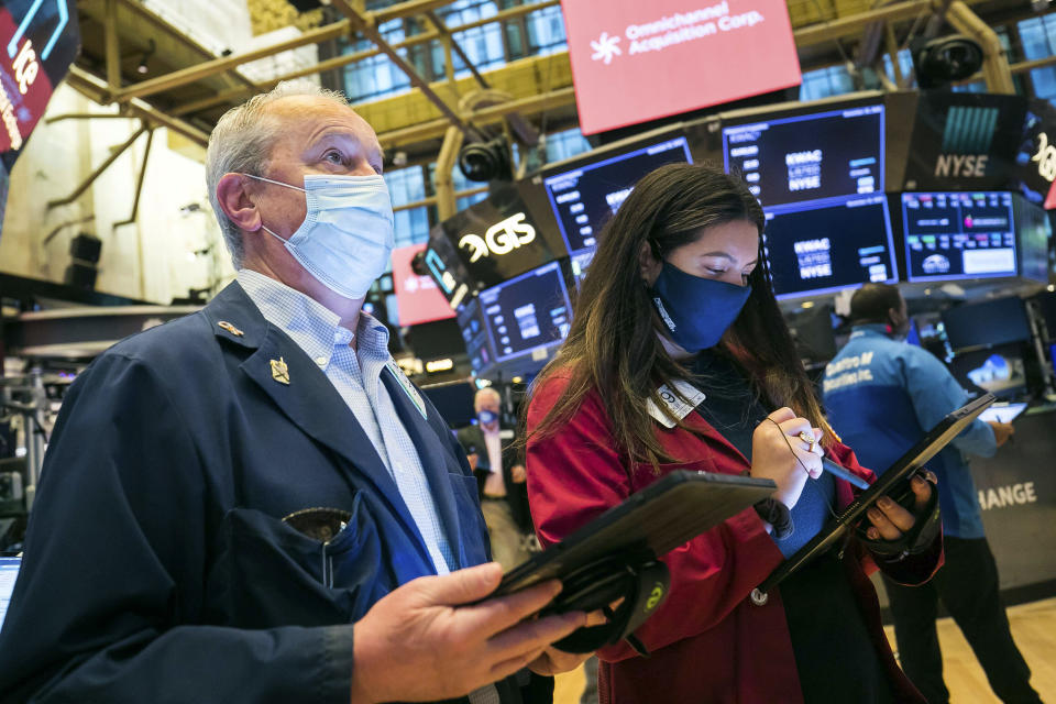 In this photo provided by the New York Stock Exchange, traders James Riley and Ashley Lara work on the floor Friday, Nov. 20, 2020. U.S. stocks are pulling a bit lower in midday trading Friday as worries about the worsening pandemic weigh on rising optimism about a coming coronavirus vaccine. (Courtney Crow/New York Stock Exchange via AP)