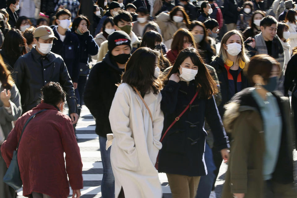 People wearing face masks to help curb the spread of the coronavirus walk around the scrambled intersection at the Shibuya shopping district in Tokyo Saturday, Dec. 26, 2020. Tokyo has confirmed 949 new cases of the coronavirus on Saturday, a record high for the Japanese capital, as the country struggles with an upsurge that is spreading nationwide. (Kyodo News via AP)