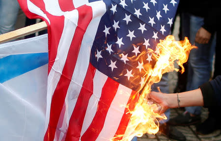 A Palestinian demonstrator burns a U.S. flag during a protest against the U.S. intention to move its embassy to Jerusalem and to recognize the city of Jerusalem as the capital of Israel, in Gaza City December 6, 2017. REUTERS/Mohammed Salem